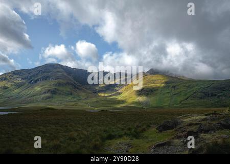 Gioco di luci e ombre attraverso la lussureggiante erba verde dei pendii di montagna a Doo Lough Valley, Glencullin Mountain, Contea di Mayo, Irlanda Foto Stock