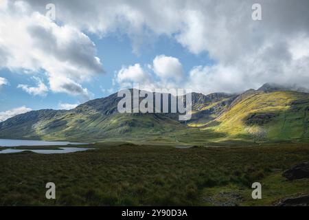 Gioco di luci e ombre attraverso la lussureggiante erba verde dei pendii di montagna a Doo Lough Valley, Glencullin Mountain, Contea di Mayo, Irlanda Foto Stock