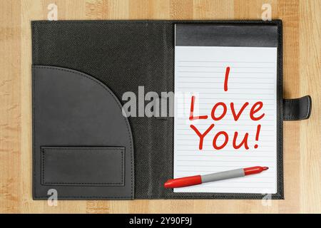 Foto orizzontale di un pad legale junior con i LOVE YOU in rosso e un pennarello rosso. Sfondo in legno. Foto Stock