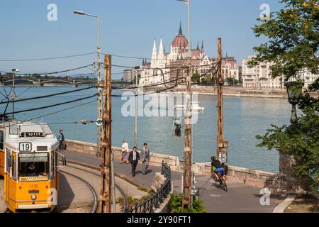 Boedapest, Ungheria 13 settembre 2008. Aspetto urbano dell'edificio del Parlamento ungherese con gente, un tram giallo e il fiume Danubio con la barca Foto Stock