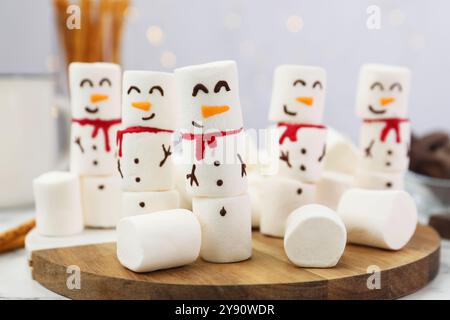 Simpatici pupazzi di neve fatti con marshmallow su tavola bianca, primo piano Foto Stock