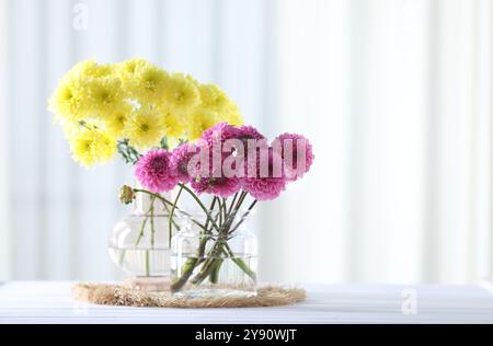 Splendidi fiori in vasi su un tavolo di legno bianco a casa. Spazio per il testo Foto Stock