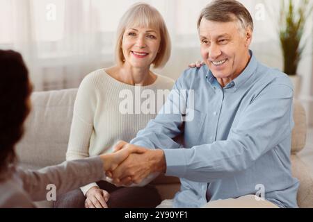 Coppia matura felice che dà al medico una stretta di mano Foto Stock