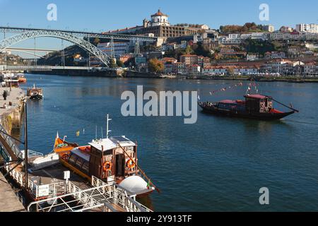 Una tradizionale Barge dei vini Porto che viaggia sul fiume Douro a Porto, con l'iconico ponte Dom Luis (Ponte Luís i) sullo sfondo. Foto Stock