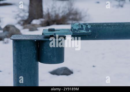 Porta chiusa a chiave su strada con sfondo nevoso della foresta. In tarda giornata. Foto Stock