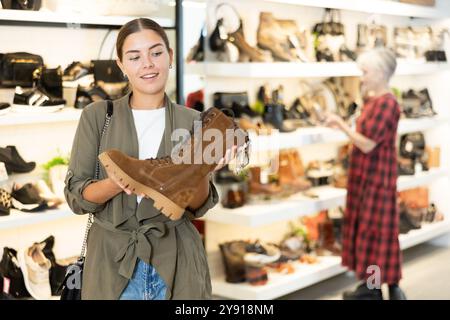 L'acquirente femminile guarda le calzature della nuova collezione e acquista un nuovo paio di stivali per l'inverno. Foto Stock