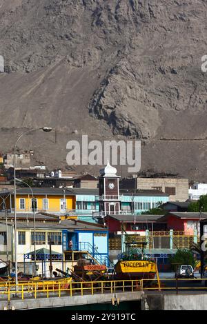 Barche da pesca in legno sulla banchina del porto, torre dell'orologio Coya Sur sullo sfondo, Tocopilla, Cile Foto Stock