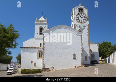Edificio bianco con torre dell'orologio, circondato da tranquille strade acciottolate, chiesa Igreja de Santa Maria do Castelo, Tavira, Faro, Algarve, Portogallo Foto Stock