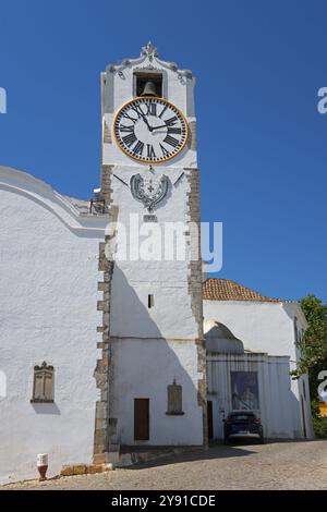 Alta torre storica dell'orologio fatta di edificio bianco con vista del cielo limpido, Torre do relogio, Chiesa di Santa Maria do Castelo, Tavira, Faro, Algarve, Portu Foto Stock