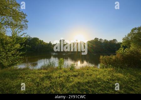 Meno calmo con alberi circostanti e raggi del sole che splendono tra le foglie, autunno, tramonto, Grossheubach, Miltenberg, Main, Spessart, Baviera, Germania, e Foto Stock