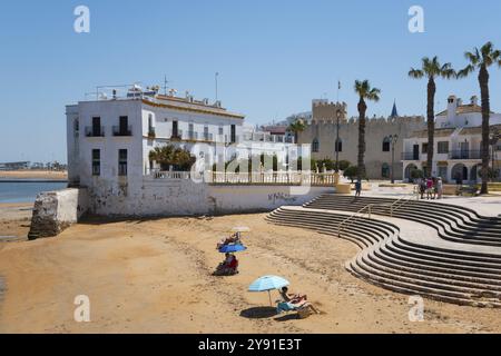 Spiaggia con edifici e palme in una giornata di sole, Plaza del Castillo, Costa de la Luz, Chipiona, provincia di Cadice, Cadice, Andalusia, Spagna, EUR Foto Stock