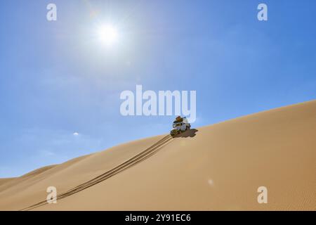 Il veicolo fuoristrada attraversa una duna di sabbia sotto un cielo azzurro nel deserto, Matruh, Great Sand Sea, deserto libico, Sahara, Egitto, Nord Africa, AF Foto Stock