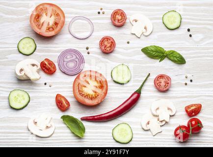 Cucina di base: Preparati ingredienti freschi, basilico, pomodori ciliegia, funghi, cetriolo tagliato, cipolla, peperoncino, spezie su legno bianco bac Foto Stock