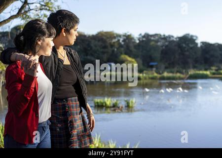 Romantica coppia LGBT di giovani donne che si abbracciano mentre guardano il lago Foto Stock