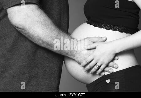 Donna incinta in piedi tocca il ventre con uomo Foto Stock