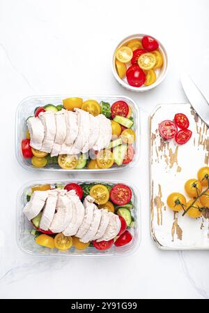 Sana preparazione del pasto per il pranzo, dieta filetto di pollo bollito con insalata di verdure in contenitori per il pranzo vista dall'alto sul tavolo da cucina in marmo bianco backgro Foto Stock