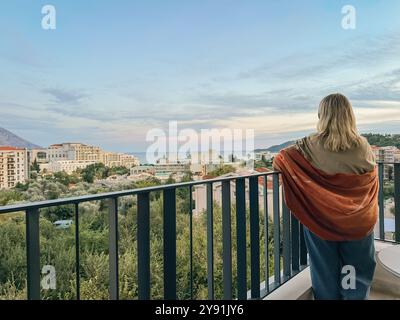 Una donna in piedi sul balcone al tramonto estivo in Montenegro Foto Stock