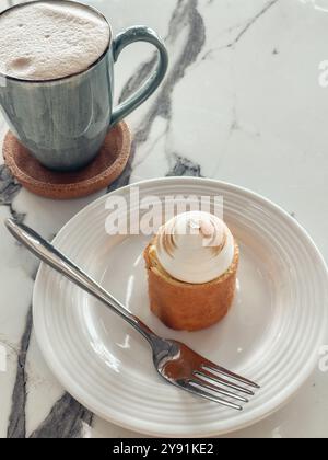 Caffè in tazza blu e torta al limone con meringa sul tavolo di marmo Foto Stock