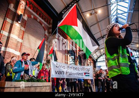 Nijmegen, Paesi Bassi. 7 ottobre 2024. Una donna con una sciarpa palestinese viene vista urlare slogan contro Israele durante la manifestazione. Nel giorno che segna un anno di attacchi di Hamas, e il bombardamento ininterrotto di Gaza da parte del governo israeliano, centinaia di persone si sono riunite nella sala principale della stazione ferroviaria centrale di Nijmegen per continuare a chiedere un cessate il fuoco a Gaza. Credito: SOPA Images Limited/Alamy Live News Foto Stock