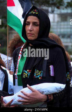 Lima, Perù. 7 ottobre 2024. Donna che indossa un hijab che trasporta una bambola che simula un bambino morto quando decine di manifestanti sono scesi in piazza a Lima in solidarietà con la Palestina e il Libano per celebrare il primo anniversario della guerra tra Israele e Hamas, iniziata il 7 ottobre 2023, quando Hamas ha ucciso e rapito israeliani al festival musicale Nova. Credito: Fotoholica Press Agency/Alamy Live News Foto Stock