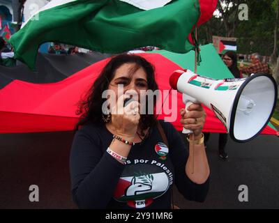 Lima, Perù. 7 ottobre 2024. Donna con altoparlante a capo di una gigantesca bandiera palestinese quando decine di manifestanti sono scesi in piazza a Lima in solidarietà con la Palestina e il Libano per celebrare il primo anniversario della guerra tra Israele e Hamas, iniziata il 7 ottobre 2023, quando Hamas ha ucciso e rapito israeliani al festival musicale Nova. Credito: Fotoholica Press Agency/Alamy Live News Foto Stock