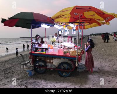 Carrello colorato su una spiaggia sabbiosa durante il tramonto con persone sullo sfondo. Foto Stock