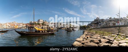 Porto, Portogallo - 12 settembre 2024: Vista panoramica delle barche sul fiume Douro con l'iconico ponte di Porto in una giornata di sole Foto Stock