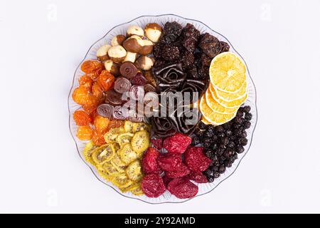 Un assortimento di frutta secca, tra cui arance, more e rotoli artistici di frutta a forma di rosa su un piatto decorativo Foto Stock