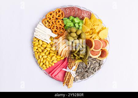 Vassoio di spuntini con pretzel, semi di girasole, pistacchi, olive, sottaceti, patatine e grissini disposti in un motivo circolare. Foto Stock