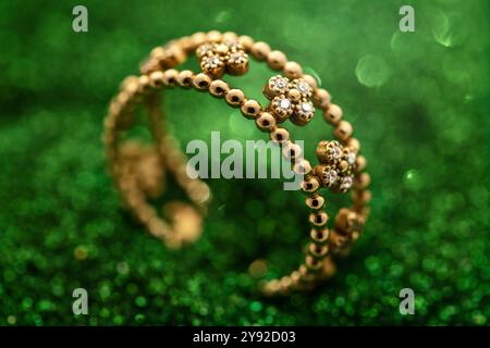 Primo piano di un anello floreale in oro e diamanti su sfondo verde scintillante Foto Stock