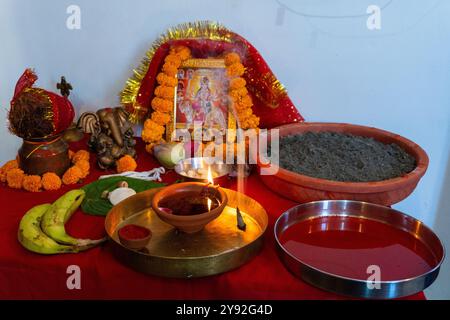 Una lampada di fango in fiamme (diya) circondata da fiori vibranti durante Navratri, un festival indù che celebra le dee indiane. Catturato a Uttarakhand, India. Foto Stock