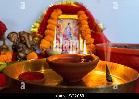 Una lampada di fango in fiamme (diya) circondata da fiori vibranti durante Navratri, un festival indù che celebra le dee indiane. Catturato a Uttarakhand, India. Foto Stock