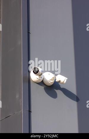 C'è una telecamera di sicurezza montata sul lato di un grande edificio che si affaccia sull'area per scopi di sorveglianza Foto Stock