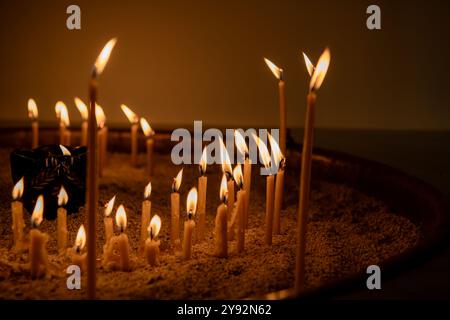 Bruciare le candele al buio. Profondità di campo ridotta. molte candele bruciate, tutto il giorno dell'anima, lume di candela Foto Stock