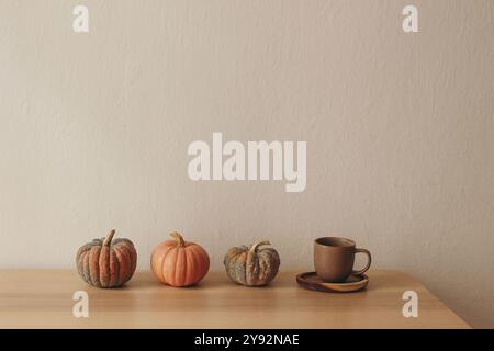 Fila di piccole zucche bianche arancioni sedute in cima a un tavolo di legno. Tazza di tè, caffè. Arredamento per la casa autunnale di Halloween. Vacanze di Thankfgiving natura morta Foto Stock