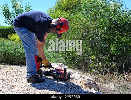 Uomo che aggiunge carburante da un barattolo di plastica alla motosega Foto Stock