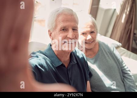 Ritratti, selfie e coppia di anziani felici in casa per amore, pov e memoria insieme. Faccia, uomo e donna scattano foto in salotto per la pensione Foto Stock