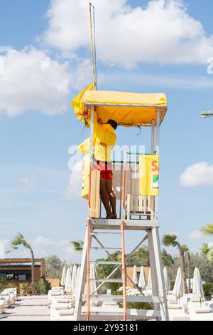 Constanta, Mamaia, Romania - 8 settembre 2023: Un soccorritore fissa un tetto di teloni su una torre di guardia. La giacca del soccorritore ha l'iscrizione 'Rescu Foto Stock