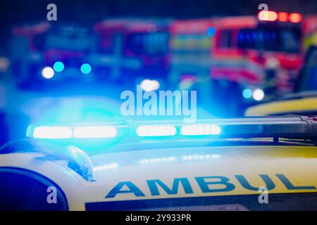 Primo piano del lampeggiatore sul tetto di ambulanza auto di servizio medico di emergenza su strada contro i motori antincendio. Temi salvataggio, incidenti e disastri. Foto Stock