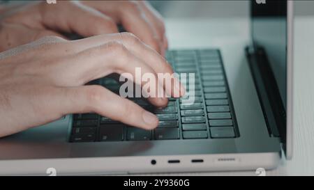 Uomo che digita sul laptop da vicino. Progetto online, rapporto di ricerca alla scrivania. Pianificazione, affari, libero professionista studente che usa un laptop che studia online lavorando da casa in Internet. Vista laterale con tonalità blu Foto Stock