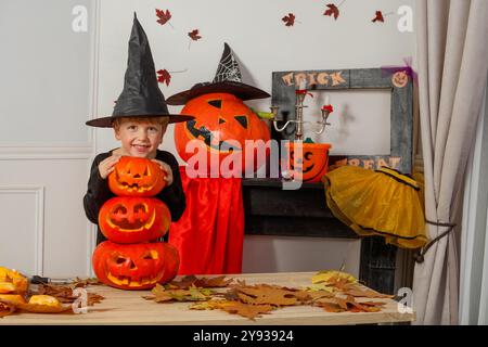 Ragazzo sorridente in un cappello da strega con jack o lanterne di Halloween Foto Stock