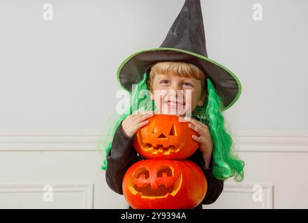 Felice mago con parrucca verde abbraccio zucche di Halloween arancioni Foto Stock