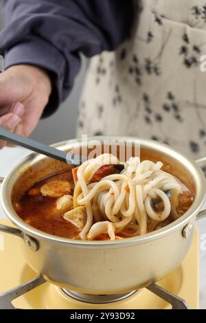 Donna che fa bollire Udon con salsa piccante, cucina passo dopo passo Foto Stock