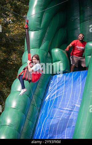 Sotto un occhio vigile, la giovane ragazza cavalca la zip Line di Amazon durante la festa del Putnam Valley Town Day del 2024 nella contea di Putnam, New York. Foto Stock