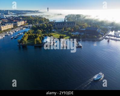 Veduta aerea ad angolo alto delle isole Skeppsholmen e Djurgarden a Stoccolma, Svezia, con la nebbia mattutina che si sposta sull'acqua calma Foto Stock