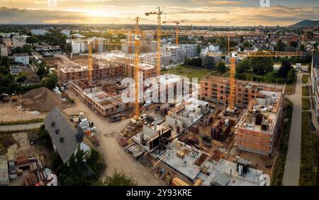 Vista aerea di un cantiere con diverse gru al tramonto. Colori caldi e retroilluminazione con il sole Foto Stock