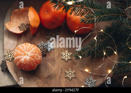 Natura morta natalizia su uno sfondo di legno con mandarini, rami di abete e fiocchi di neve. Biglietto di Natale con posto per il testo. Foto Stock