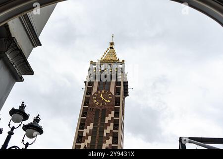 Un'immagine sorprendente di una torre dell'orologio ornata, catturata da un angolo basso contro un cielo nuvoloso, che mostra elementi architettonici dettagliati tipici Foto Stock