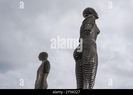 Questa straordinaria immagine cattura le dinamiche statue di Ali e Nino incastrate, poste contro un cielo nuvoloso drammatico, simboleggiando l'amore e il cultur eterni Foto Stock