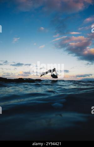 La silhouette di un surfista si affaccia su un cielo estivo che tramonta sull'oceano a Gran Canaria. Foto Stock